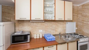 A kitchen with white cabinets, a microwave, a stove, and a sink.