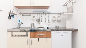 Una cocina moderna con lavavajillas integrado, un fregadero de acero inoxidable y una variedad de utensilios colgando sobre la encimera.