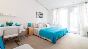 Un dormitorio con cama, escritorio y silla. Hay una ventana con cortinas y un cuadro en la pared.