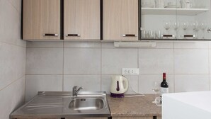 A modern kitchen with a stainless steel sink, a kettle, and wine glasses on the counter. - Apartments Djurkovic - Two-Bedroom Apartment with Shared Terrace and Sea View (Mlini)