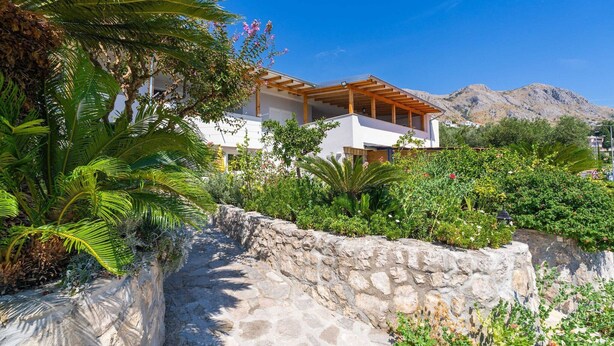 A modern house with a stone pathway leading to a wooden pergola. - Apartments Djurkovic - Two-Bedroom Apartment with Shared Terrace and Sea View (Mlini)