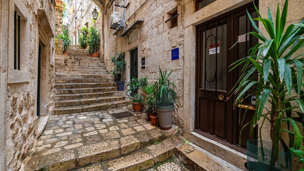 A narrow stone staircase leading to a building with a dark wooden door and a sign indicating a restaurant.