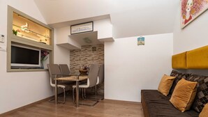 A compact living space with a dining area, a sofa, and a TV.