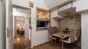 A compact living space with a dining area, a TV mounted on the wall, and a small kitchenette.