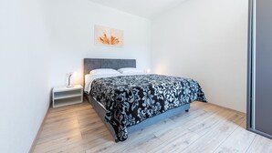 A modern bedroom with a bed, bedside table, and a wall-mounted artwork.