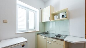 A compact kitchen with a window, a built-in sink, and a small refrigerator.