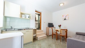 A compact kitchen with a dining area, a sofa, and a TV.