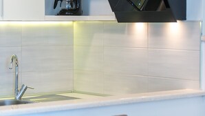 Una cocina moderna con un lavamanos de acero inoxidable, azulejos blancos y una campana extractora integrada.