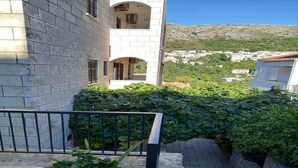 Un bâtiment doté d’une façade en pierre, d’un balcon et offrant une vue sur une ville située sur une colline.