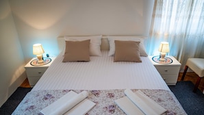 A neatly made bed with two pillows, a bedside table with a lamp, and a small chair. - Guest House Cesic - Double Room No4 (Dubrovnik)