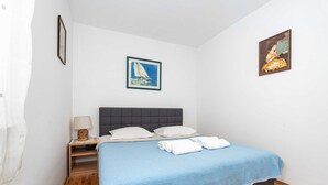 A bedroom with a bed, a nightstand with a lamp, and two framed pictures on the wall.