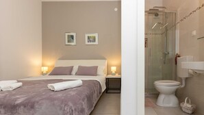 A hotel room with a bed, bedside lamps, a shower, and a toilet. - Rooms Batina - Double Room-1 (Dubrovnik)