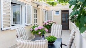 An outdoor patio with a table, chairs, potted plants, and a door. - Rooms Batina- Standard Double Room-2 (Dubrovnik)
