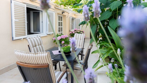 A patio with a table and chairs, surrounded by plants and a building with shutters. - Rooms Batina- Standard Double Room-2 (Dubrovnik)