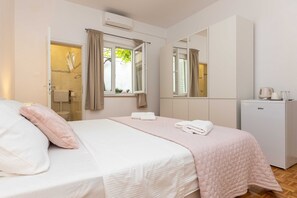 Ein Schlafzimmer mit Bett, Schrank, Spiegel und einer kleinen Küchenzeile.