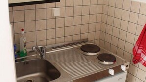 Eine kleine Küche mit Spüle, zwei Kochfeldern und einem kleinen Kühlschrank.