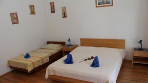 A hotel room with two single beds, a wooden headboard, a nightstand with a lamp, and a small table with a lamp. - Apartments Lozica - Standard Studio  Apartment with Terrace and Sea View (Mokosica)