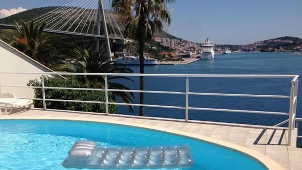 A swimming pool with a clear view of the sea and a distant cityscape. - Apartments Lozica - Standard Studio  Apartment with Terrace and Sea View (Mokosica)