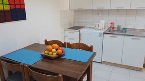 Una cocina compacta con armarios blancos, una pequeña encimera y una mesa con un mantel individual azul.