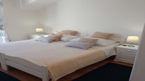 Un dormitorio con una cama, dos mesitas de noche y una mesita auxiliar.
