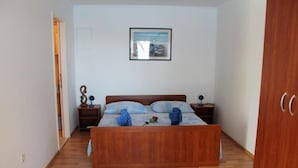 Un dormitorio con una cama de madera, una mesita de noche con una lámpara y un cuadro enmarcado en la pared.