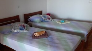 Two single beds with wooden headboards, each with a floral-patterned pillow and a rolled towel on the bed. - Apartments Franka Saplunara-Twin Room with Terrace and Sea view  No1 (Saplunara)