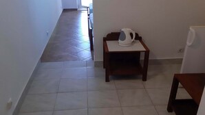 A hallway with a tiled floor, a wooden table with a kettle, and a white appliance. - Apartments Franka Saplunara-Twin Room with Terrace and Sea view  No1 (Saplunara)