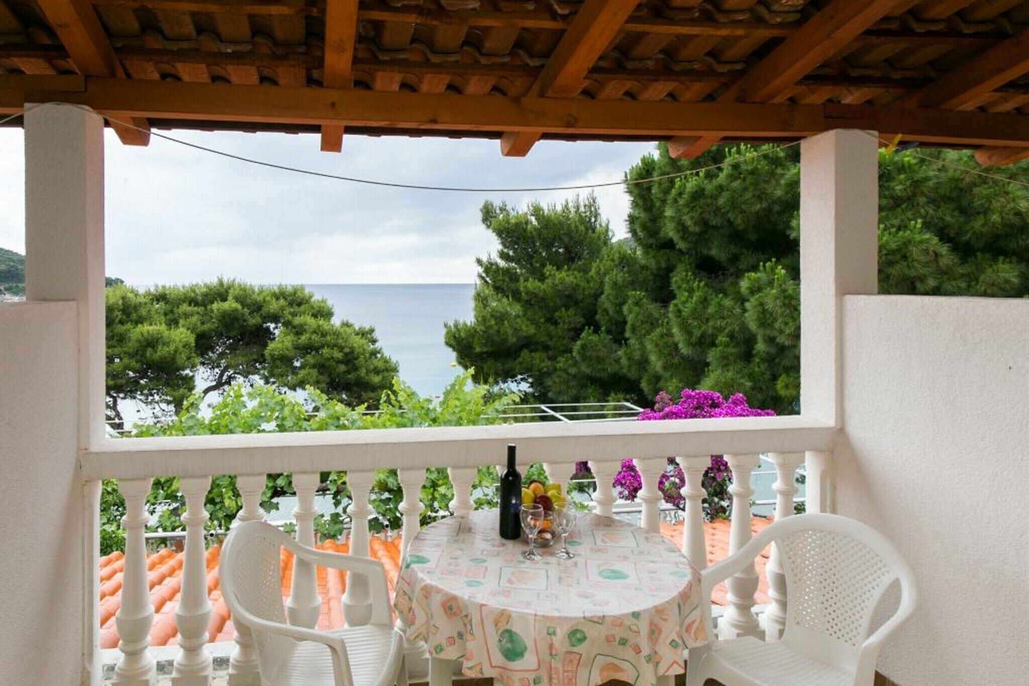 Un espace extérieur aménagé, abrité et doté d’une table et de chaises, offrant une vue sur une étendue d’eau et sur la verdure.