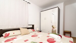 A bedroom with a bed, a wardrobe, a nightstand, and a small table.