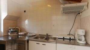 Una cocina con dos lavamanos de acero inoxidable, una cafetera y una campana extractora integrada.
