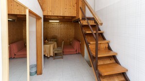 Un interior de madera con una escalera, un sofá, una mesa y una silla.