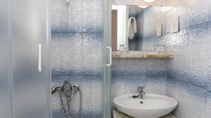 A bathroom with a glass shower enclosure, a white sink, and a mirror above it. - Lapad View Apartments - Studio Apartment with Balcony and Sea View (Dubrovnik)