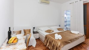 A bedroom with a bed, bedside table, and a window with curtains. - Lapad View Apartments - Studio Apartment with Balcony and Sea View (Dubrovnik)