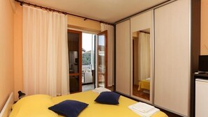 Habitación de hotel con cama, televisión y puerta corrediza que da a un balcón.