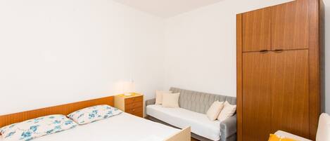 A bedroom with a bed, a sofa, a wardrobe, and a nightstand.