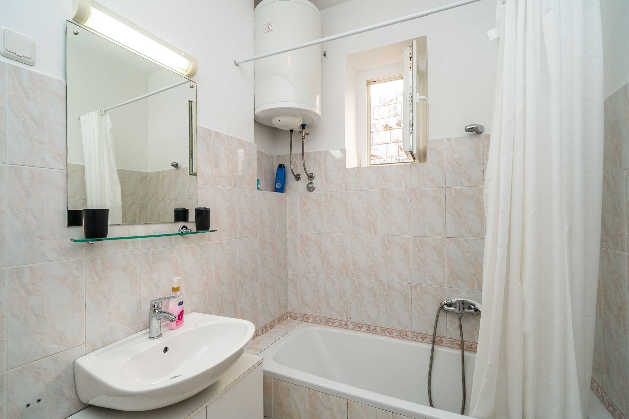 A bathroom with a white sink, mirror, and bathtub.