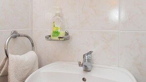 A bathroom with a white sink, a towel rack with a white towel, and a soap dispenser on a shelf. - Guest House Ljubica - Double Room with Private Bathroom-2 (Dubrovnik)