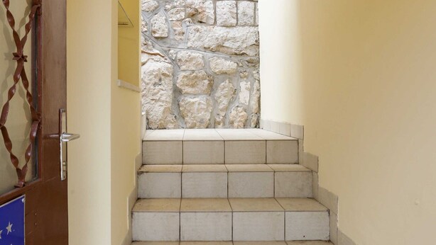 A set of beige tiled stairs leading up to a stone wall.