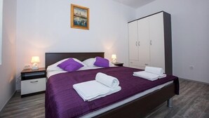 A modern bedroom with a bed, nightstands, a wardrobe, and a painting on the wall. - Villa Roza- Two-Bedroom Apartment (Mokosica)