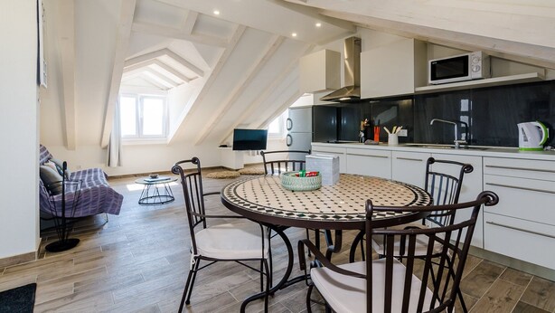 A modern kitchen with a round dining table, black chairs, and a built-in microwave.