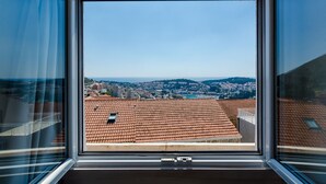 A view from a window with a clear sky, a cityscape, and terracotta rooftops.