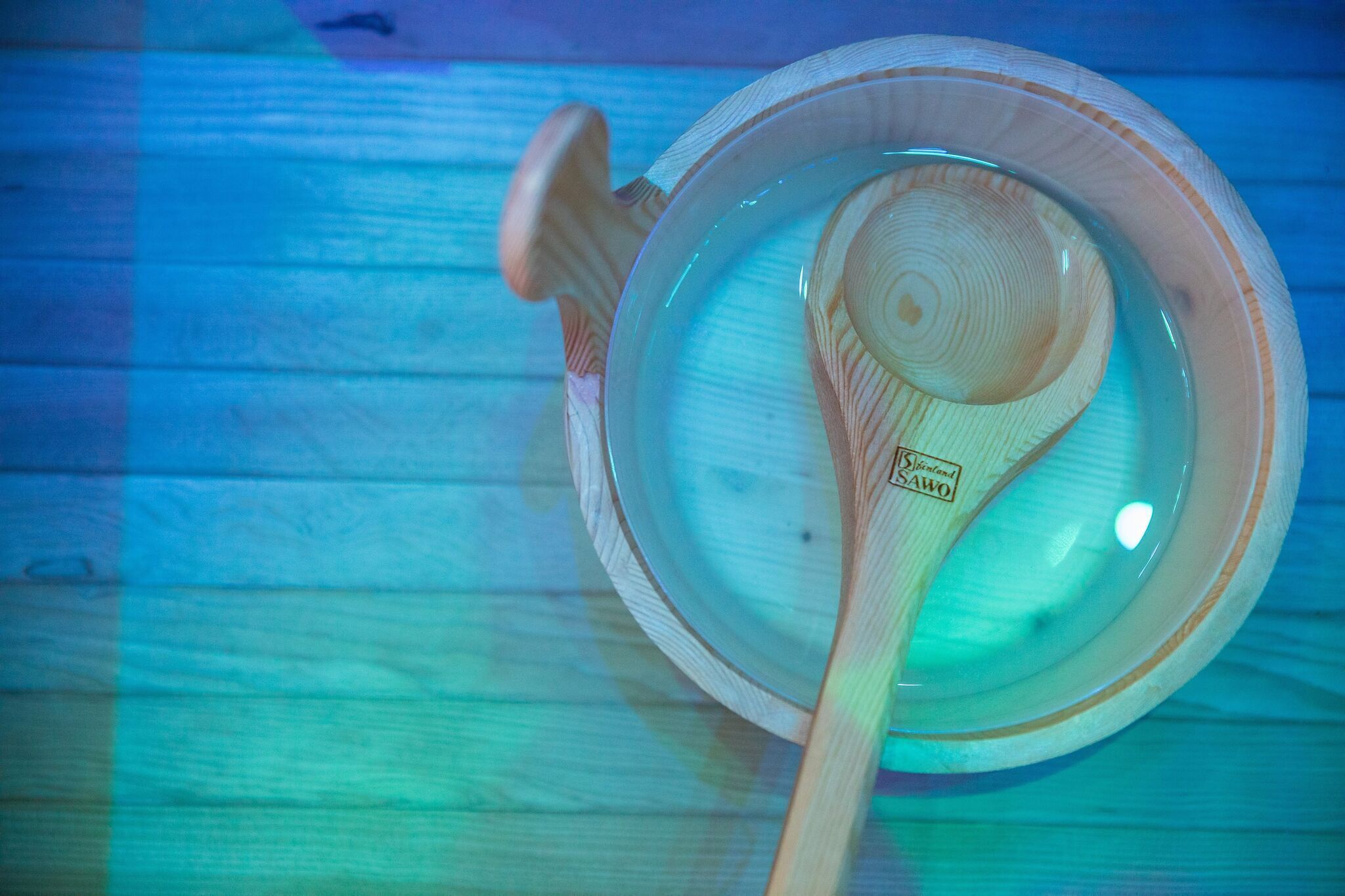 A wooden spoon resting in a clear glass bowl on a wooden surface.
