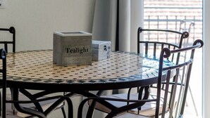 A round table with a geometric tile pattern, a box labeled "Tealight," and metal chairs with curved backs. - Apartments Life - One Bedroom Apartment with Balcony and Sea View (Dubrovnik)