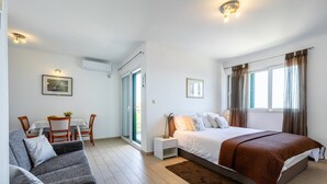 Une chambre à coucher comprenant un lit, un canapé, une table à manger avec des chaises et une fenêtre avec des rideaux.