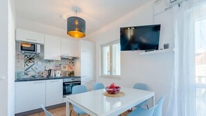 Eine moderne Küche mit weißen Schränken, einer Mikrowelle und einem Essbereich mit einem weißen Tisch und blauen Stühlen.