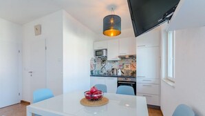 Eine moderne Küche mit weißen Schränken, einer Mikrowelle und einem Essbereich mit einem weißen Tisch und blauen Stühlen.