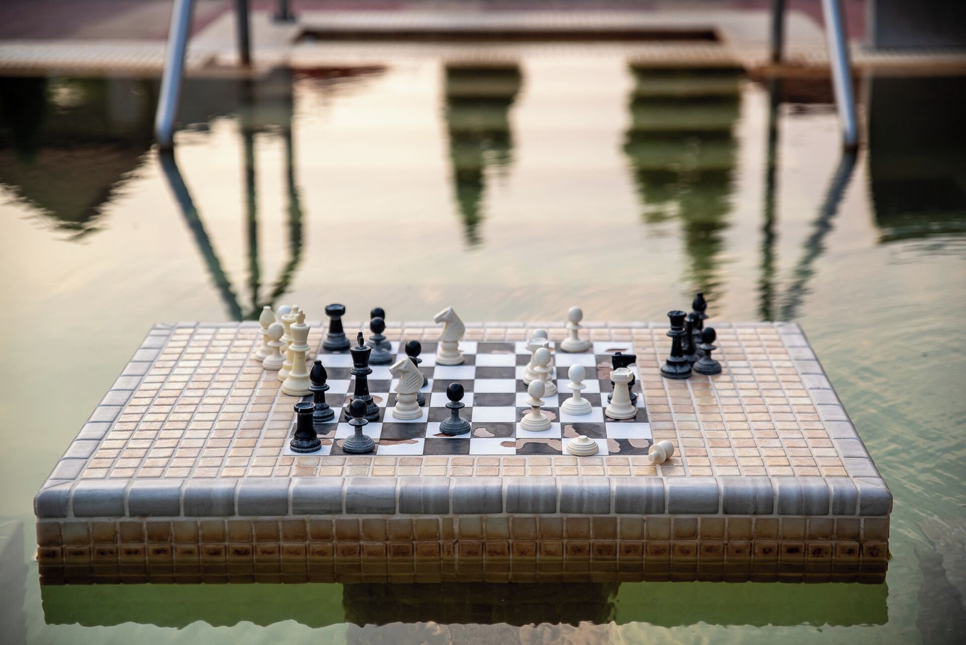 Un jeu d ’échecs installé sur une surface carrelée, près d’une piscine.