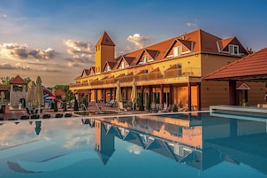 A hotel with a swimming pool, outdoor seating, and a tower structure.