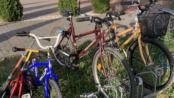 A row of bicycles parked on a rack in front of a building with a red roof and a window.