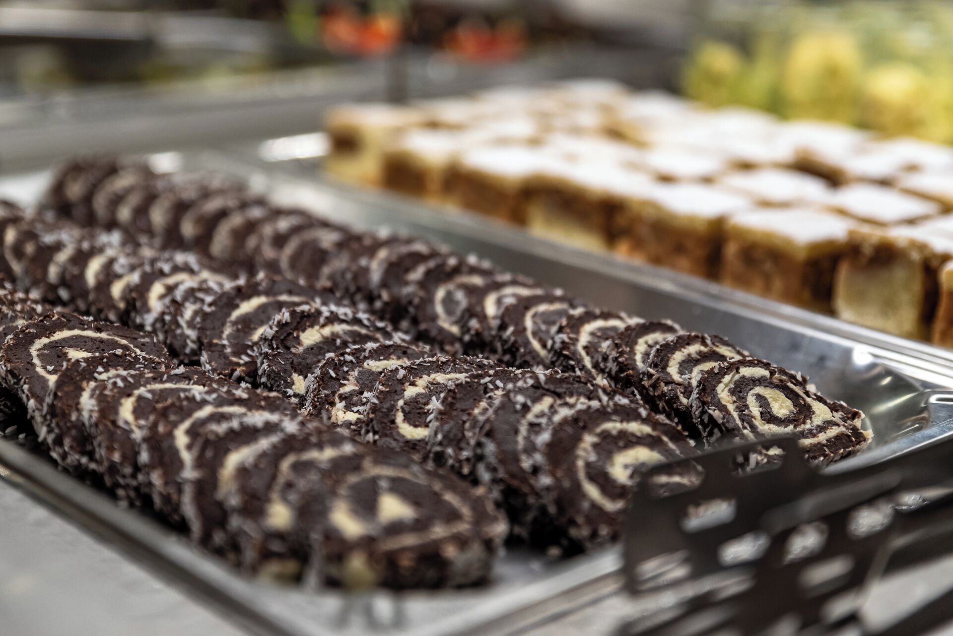 Una exhibición de varios postres, entre ellos rollos de chocolate y otras preparaciones horneadas.